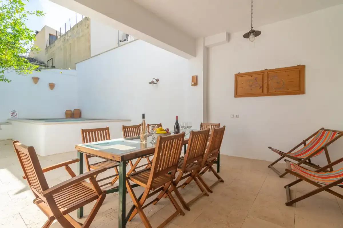 Comedor exterior cubierto con una mesa de madera y sillas plegables.