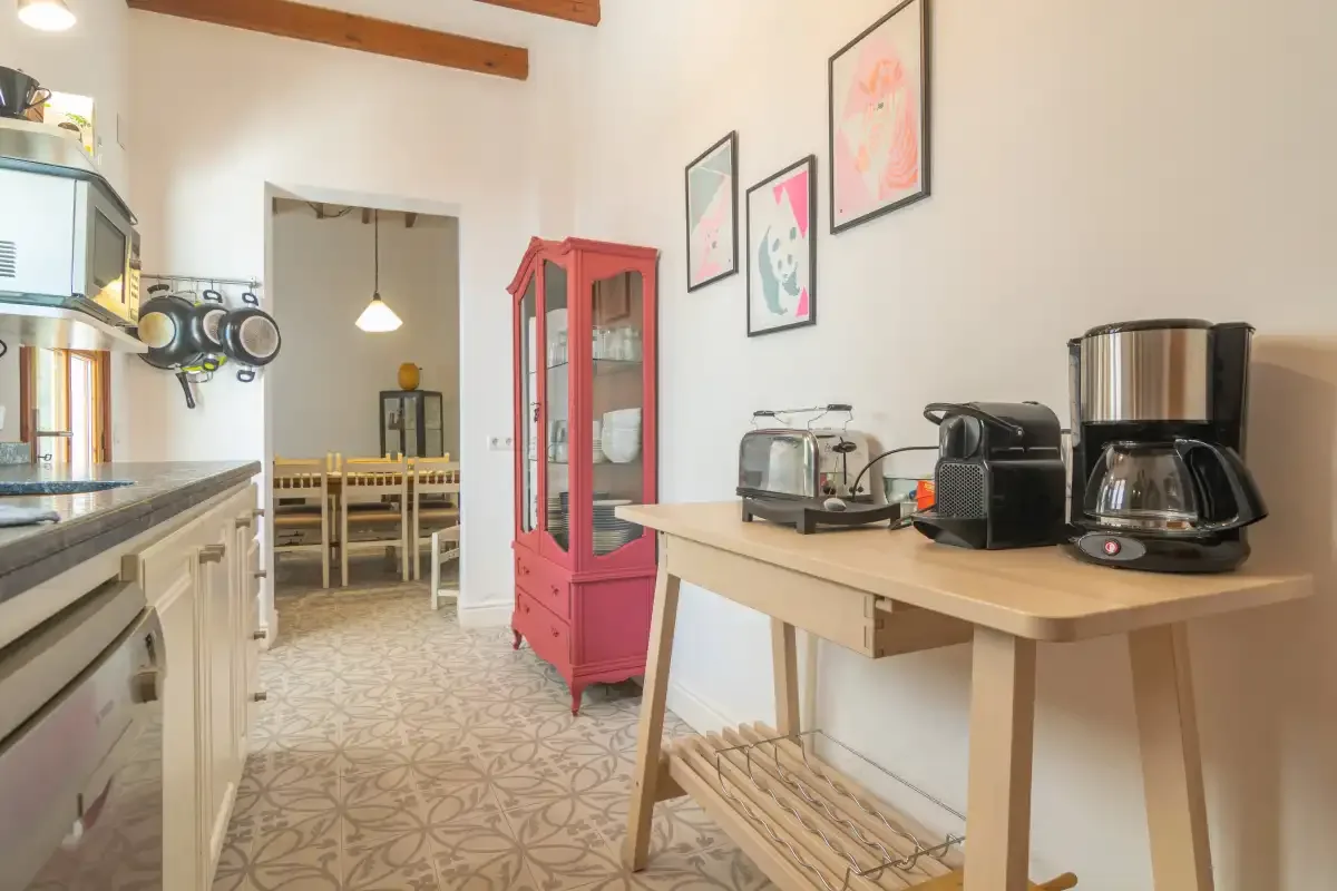 Una cocina luminosa con una encimera de madera y una mesa de comedor en la habitación contigua.