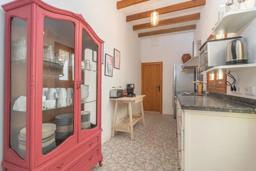 Una cocina con un armario rojo con puertas de vidrio y una encimera larga.