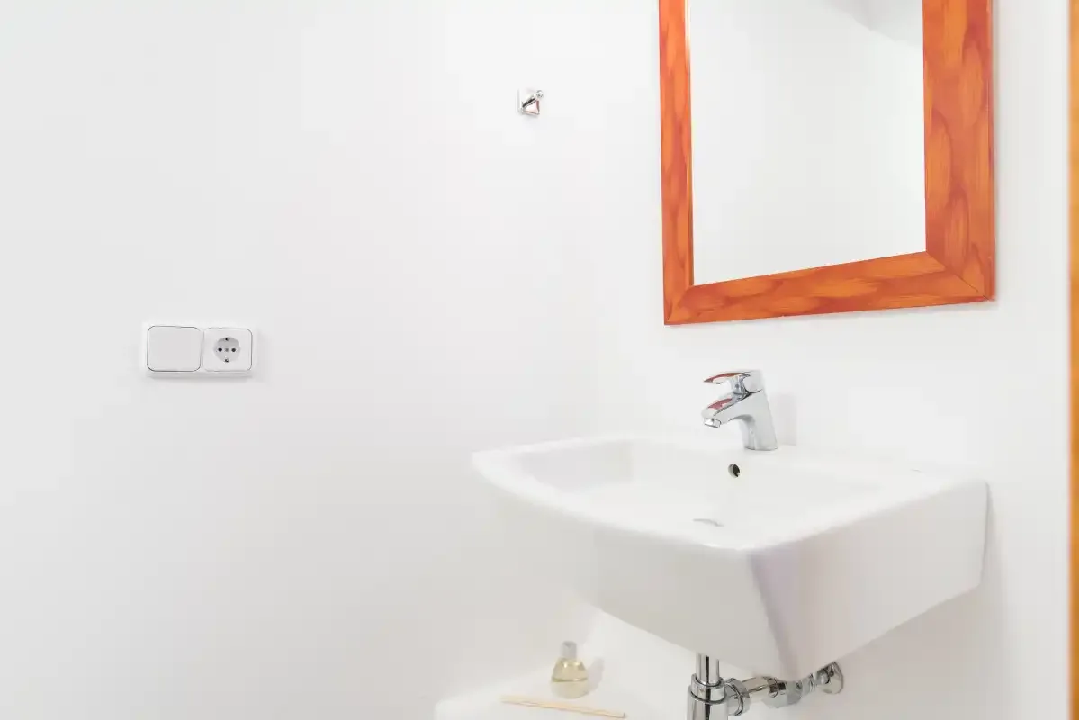 Un lavabo de baño está debajo de un espejo con marco de madera.