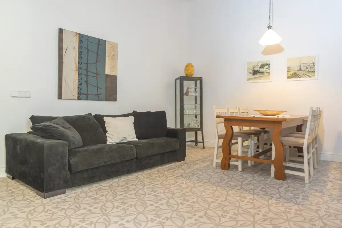 Una zona de estar y comedor con asientos oscuros, una mesa de madera y arte en las paredes.