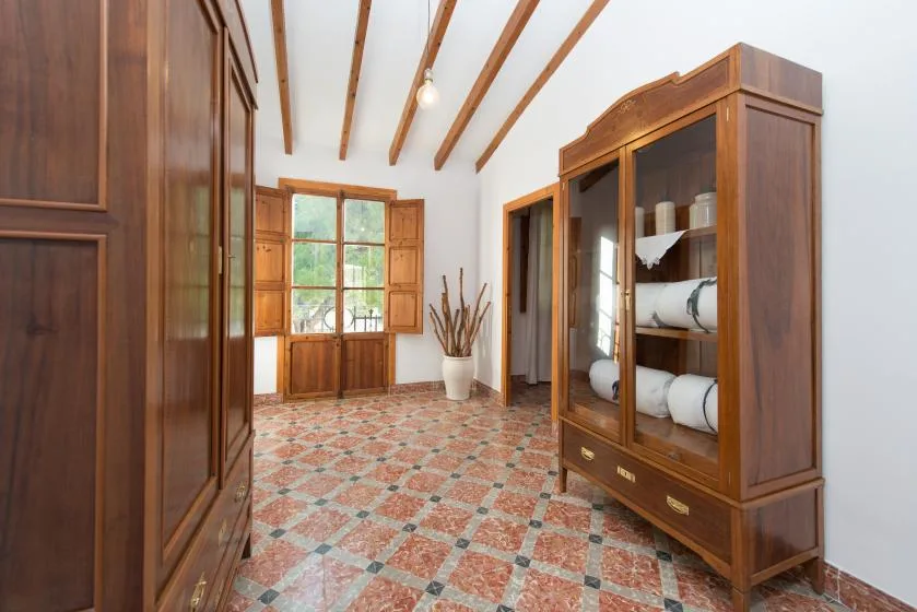 Una habitación luminosa con armarios de madera, vigas vistas y suelo de baldosas estampadas.