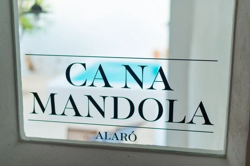 Un letrero de vidrio que dice «Ca Na Mandola» está colocado en una ventana.