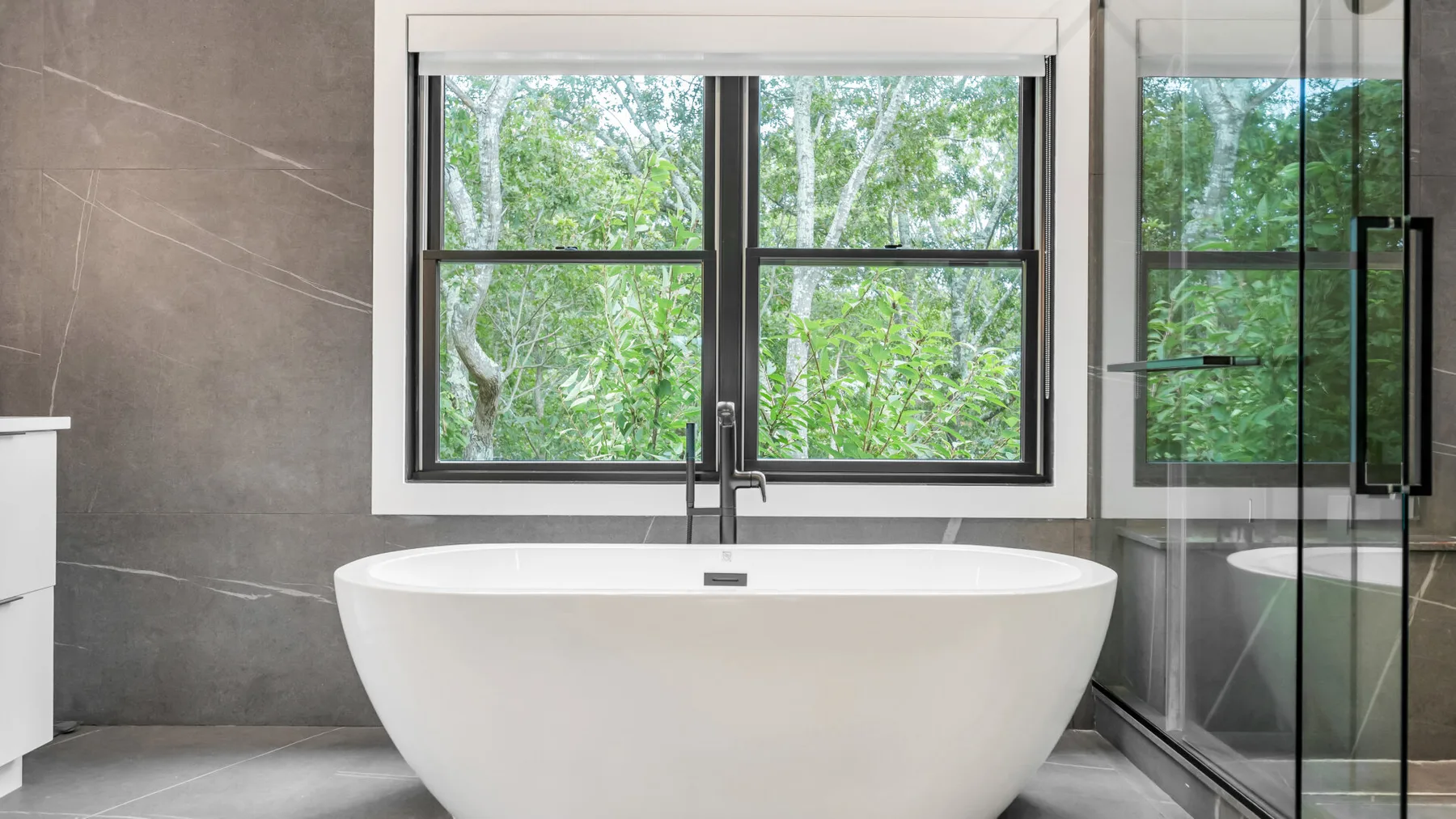Un baño con una bañera exenta junto a una ventana amplia.