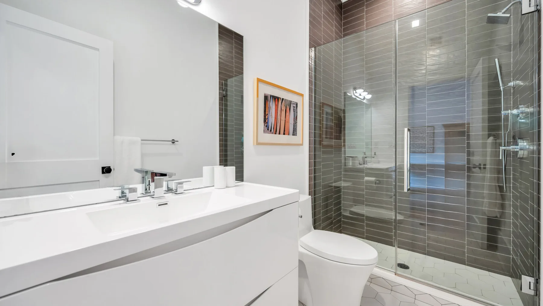 Un baño moderno con un tocador blanco y una ducha con mampara de vidrio.