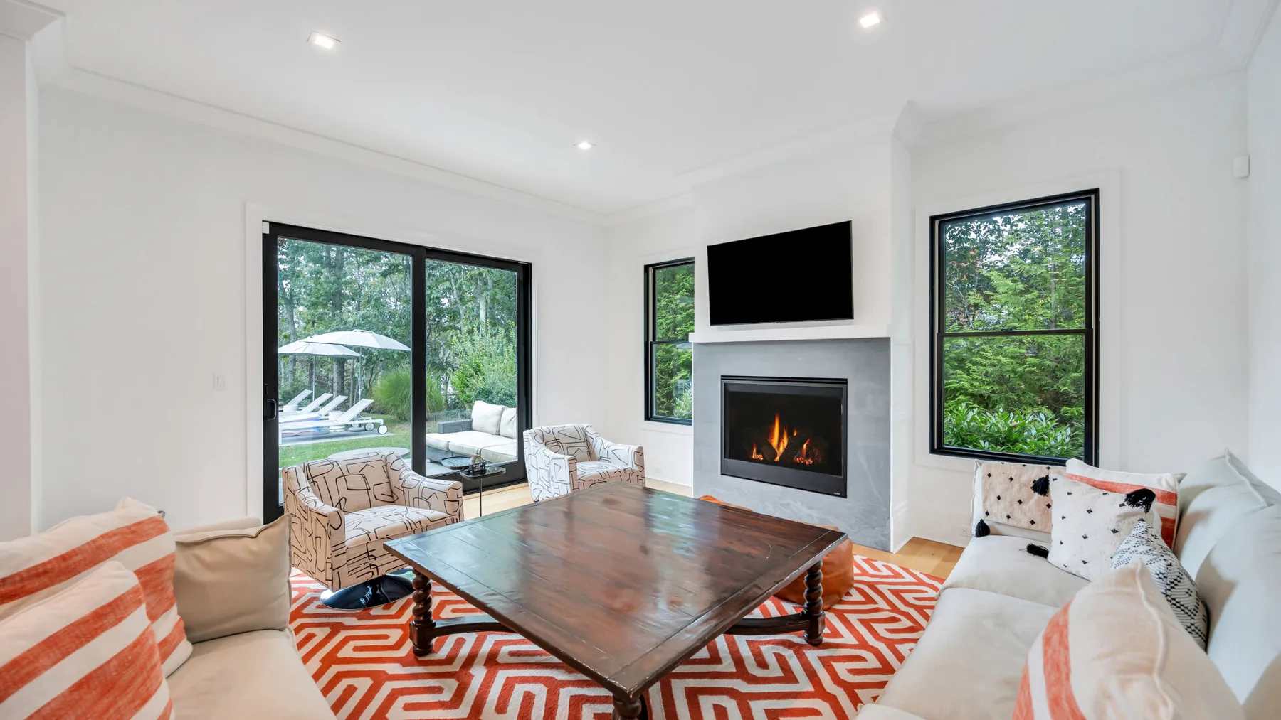 Una sala de estar luminosa con chimenea, ventanales y una mesa de centro de madera.