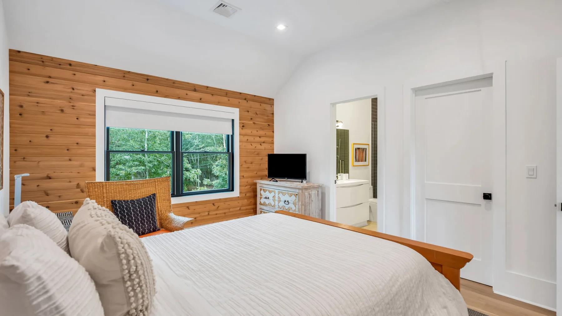 Un dormitorio con una cama grande junto a una pared revestida de madera y una ventana.