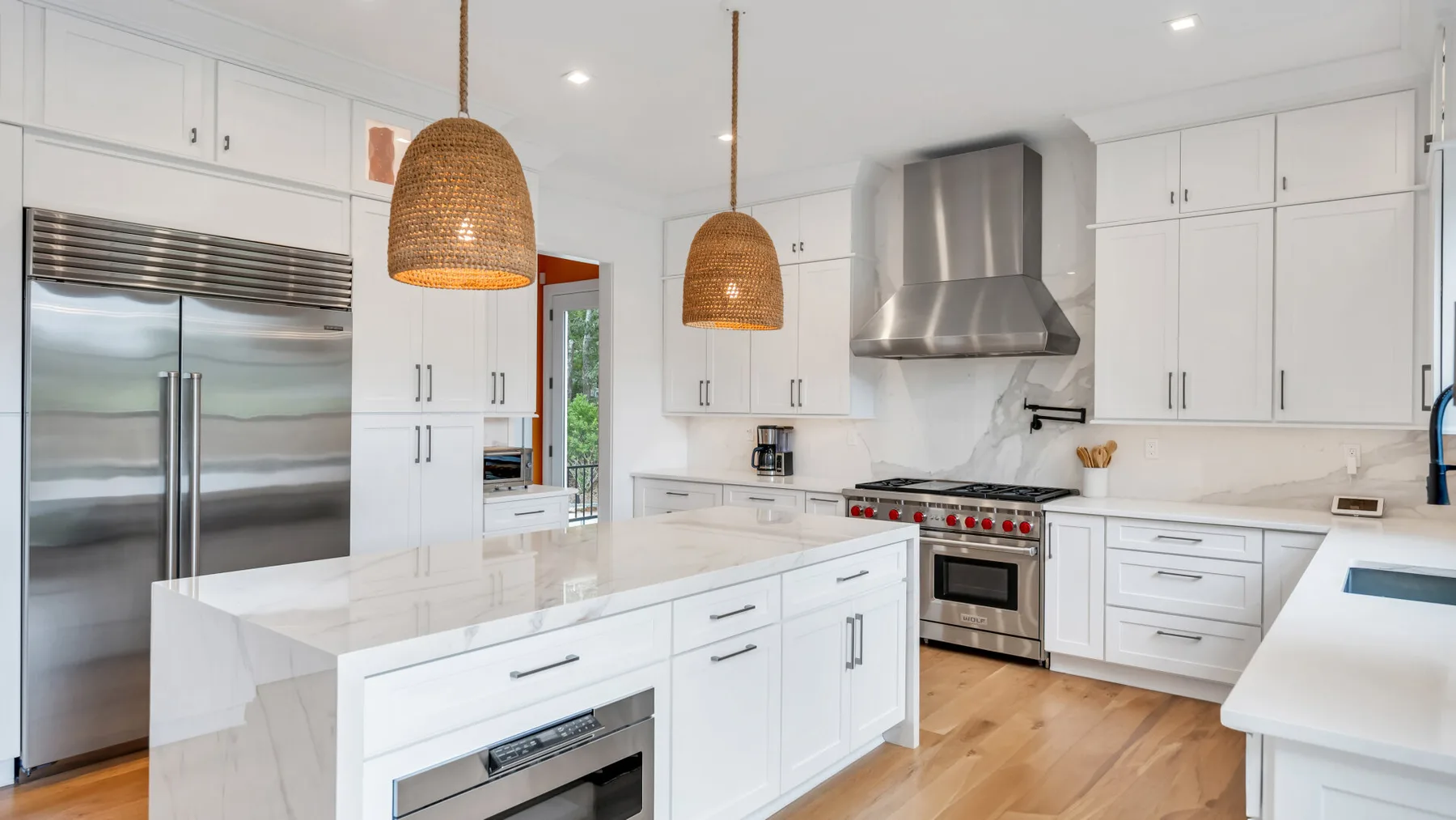 Una cocina luminosa con gabinetes blancos, una isla central y electrodomésticos de acero inoxidable.