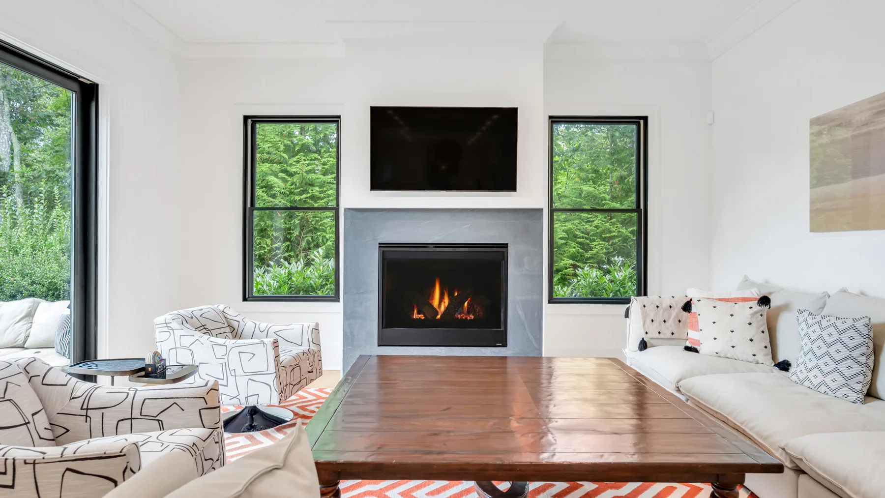 Una sala luminosa con chimenea, asientos y una amplia mesa de centro de madera.