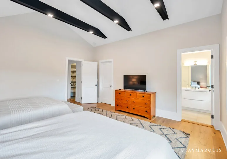 Dormitorio con camas y una cómoda con televisor.