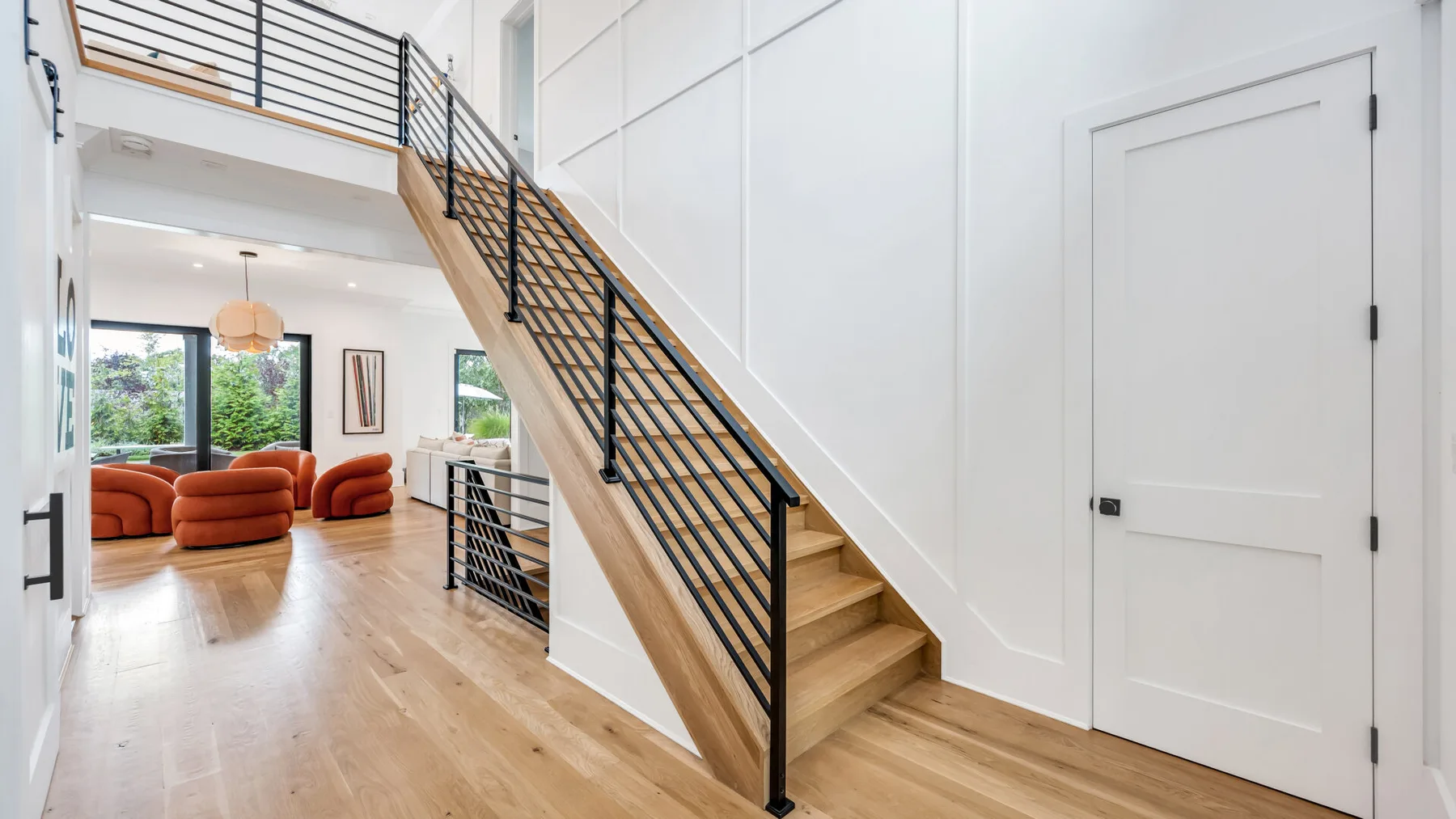 Un interior luminoso muestra una escalera que conduce a un descanso superior y una zona de estar.