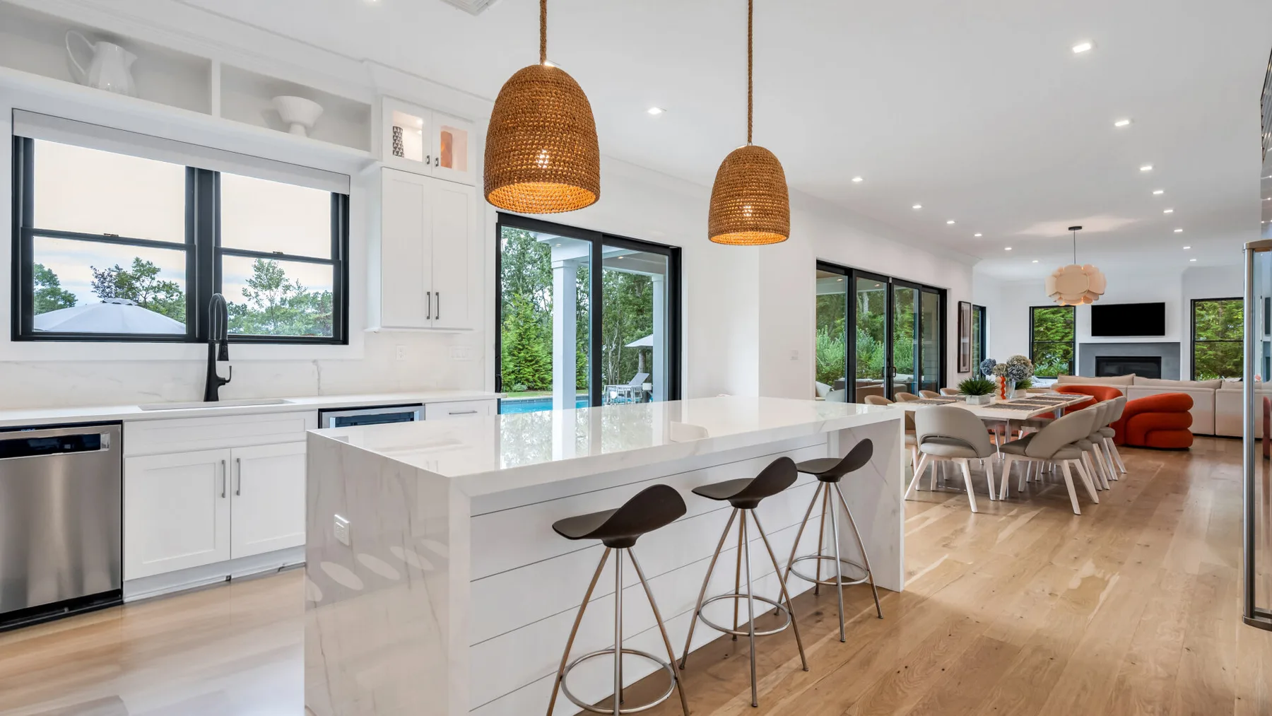 Una cocina y comedor de concepto abierto con una isla y lámparas colgantes.