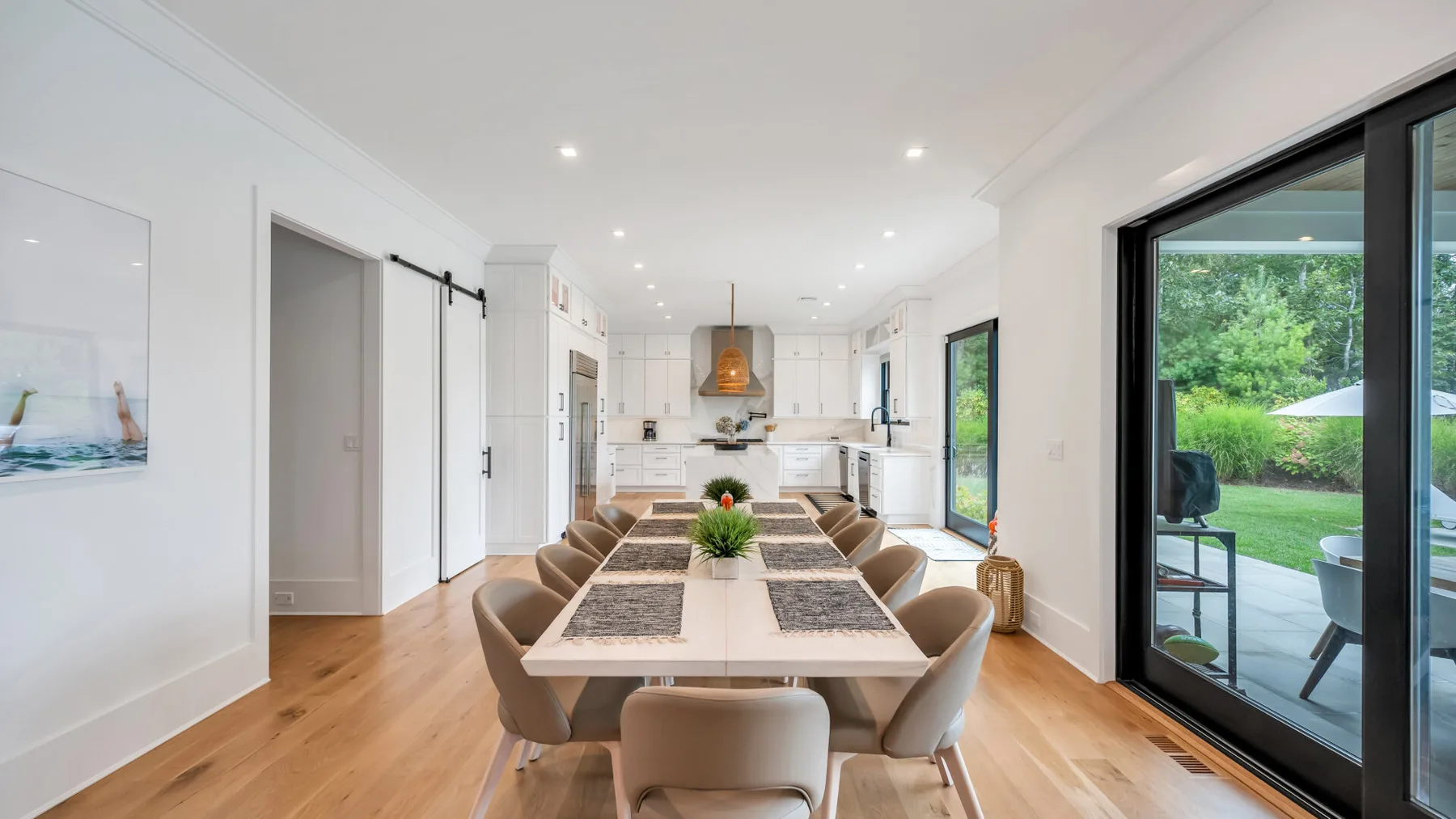Un comedor luminoso con una mesa larga junto a grandes puertas de vidrio.