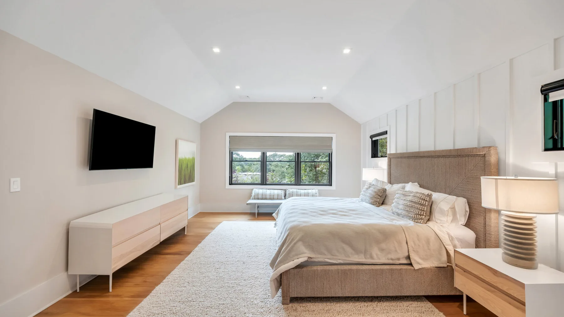 Un dormitorio luminoso con una cama grande y una ventana amplia.