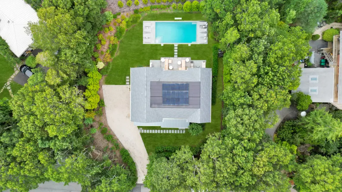 Una vista aérea muestra una casa rodeada de árboles, con una piscina cerca.