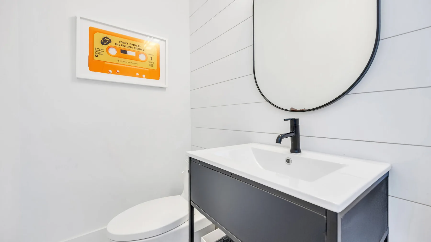 Un tocador de baño con lavabo y un espejo redondo grande.