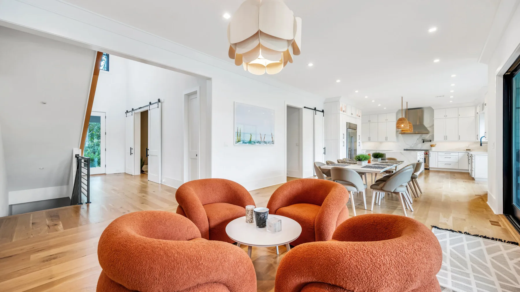 Una sala-comedor abierta con asientos naranjas y una cocina al fondo.