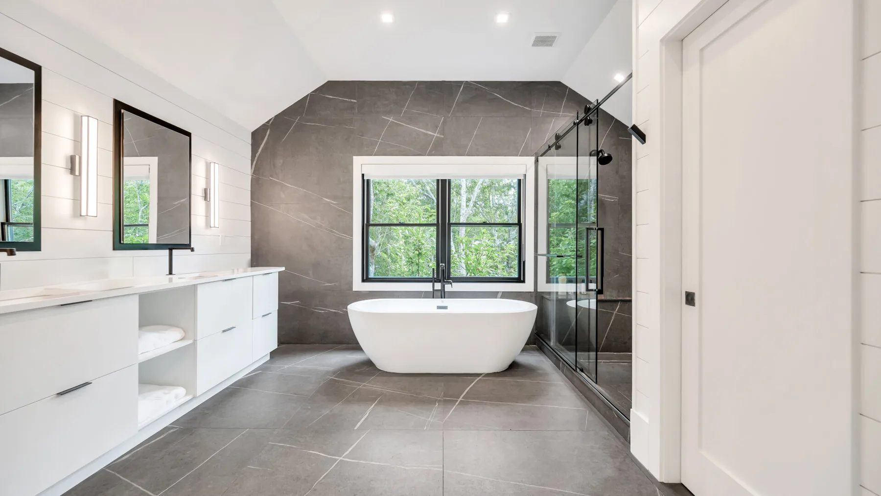 Un baño moderno con bañera exenta, tocador y ducha de vidrio.