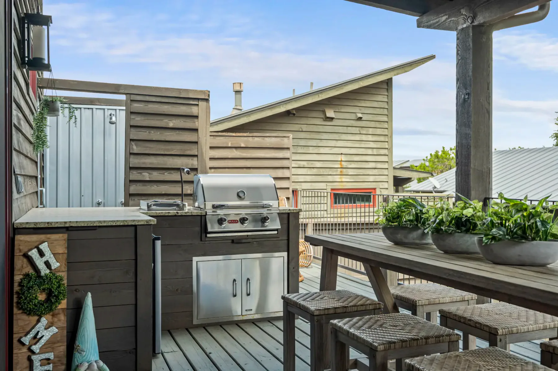 A wooden deck with a built-in grill, counter, and outdoor dining table.