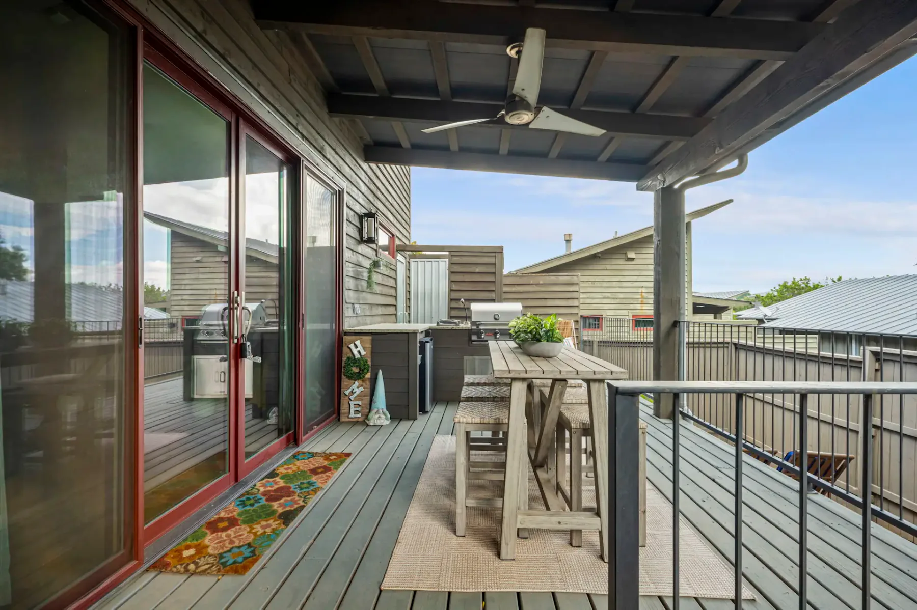 A covered deck with outdoor seating and sliding glass doors along the house.