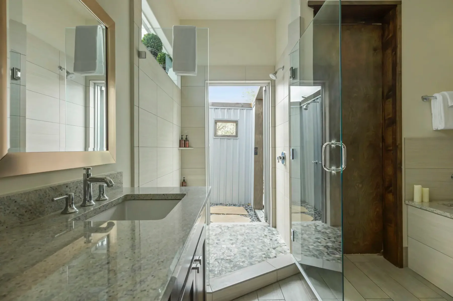 A tiled bathroom with a vanity, mirror, and glass shower.
