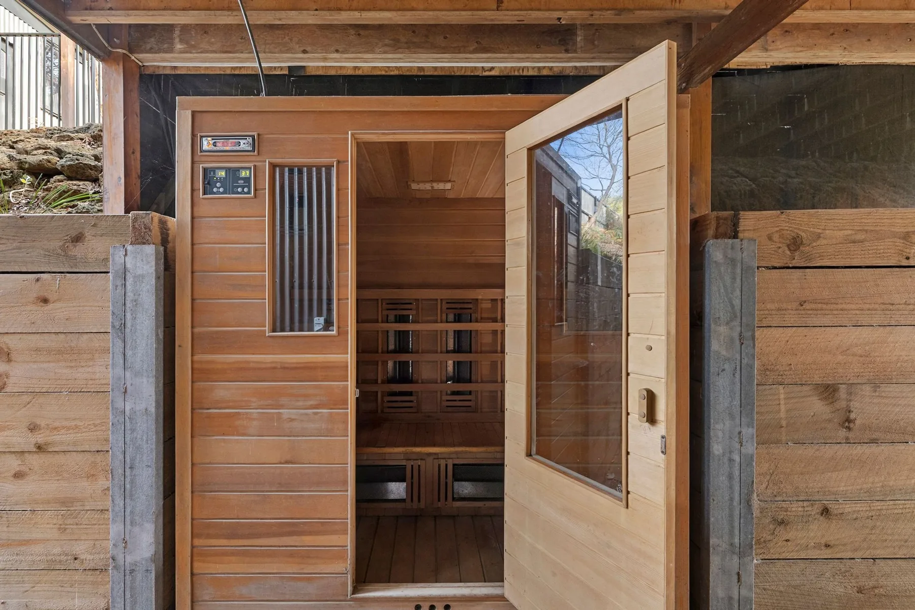 A wooden sauna doorway opens onto a small room with tiered benches.