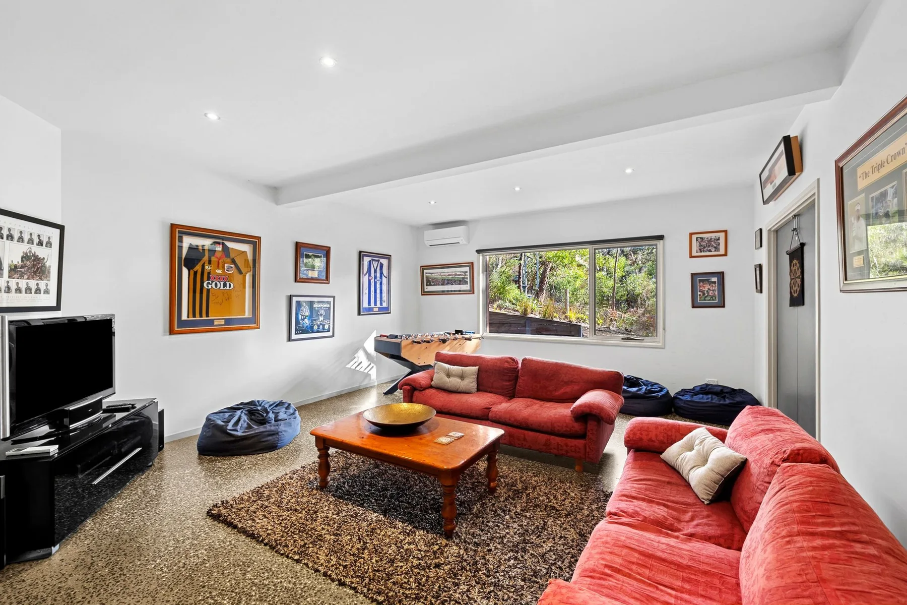 A living room with red seating, a coffee table, and framed pictures.