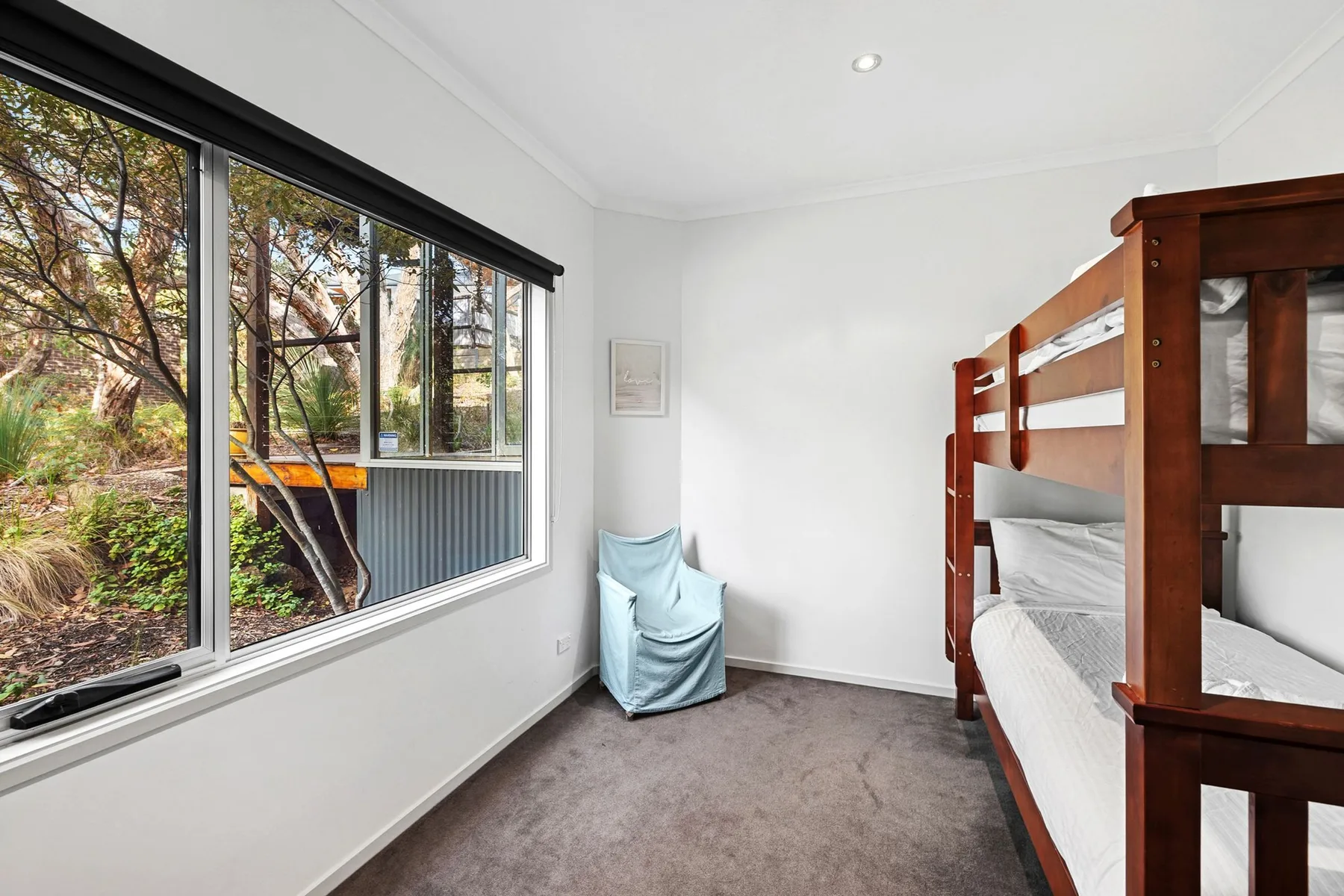 A bright bedroom with bunk beds beside a large window.