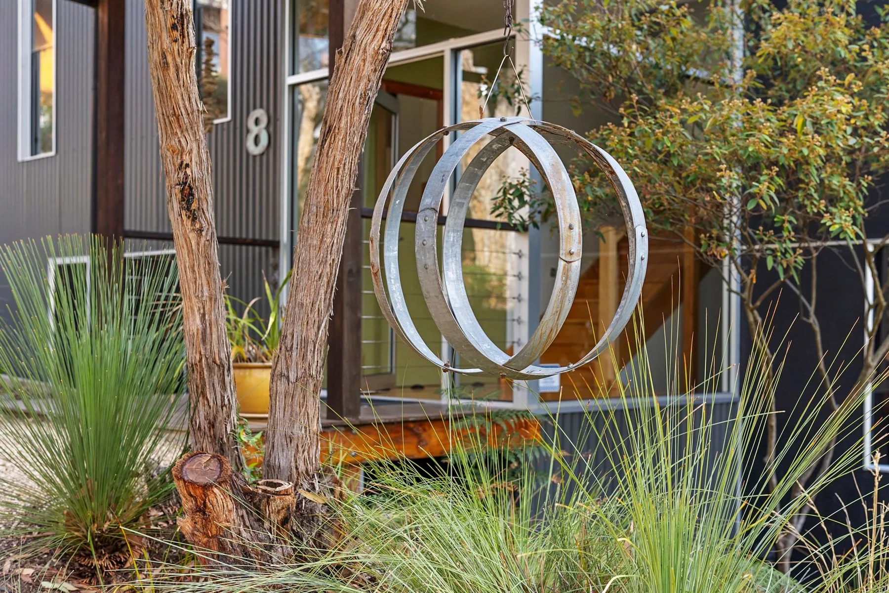 An outdoor garden area features sculptural metal rings among trees and grasses.
