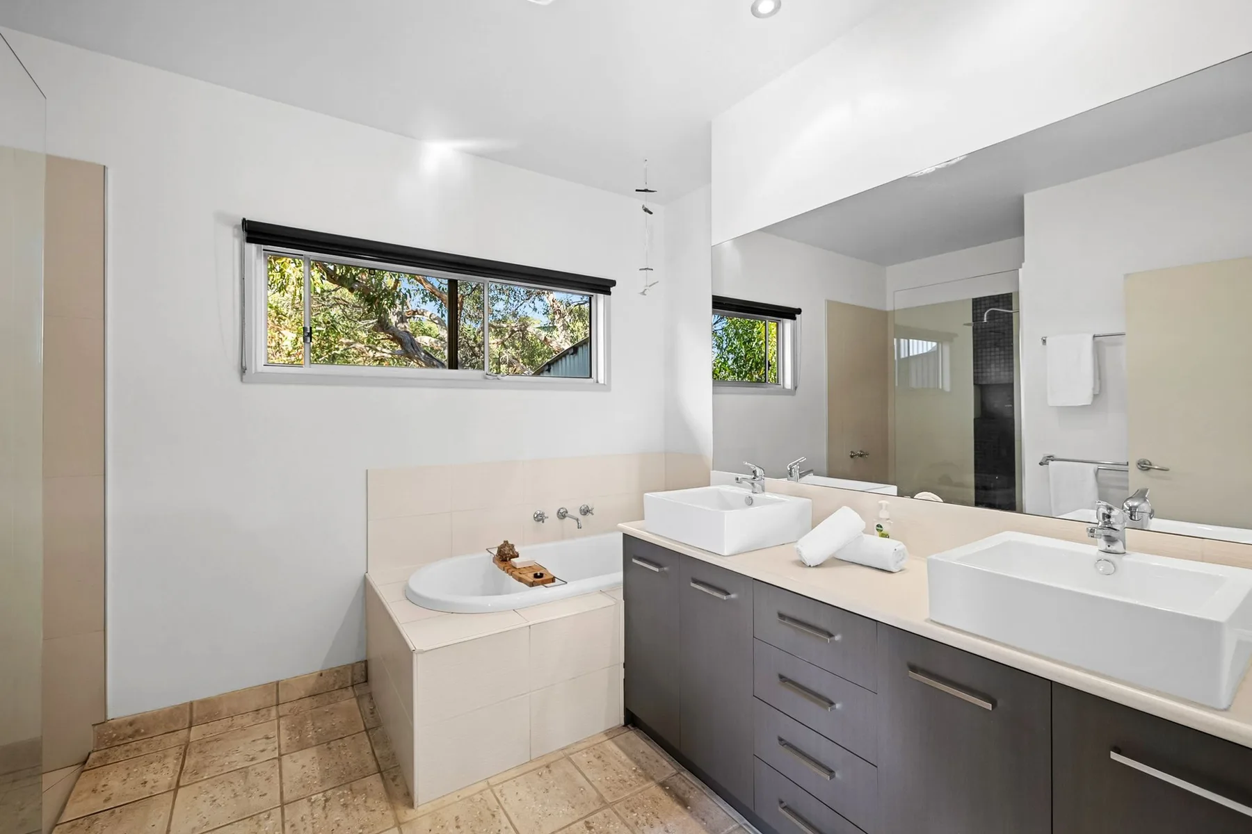 A bright bathroom with a long vanity, sinks, and a bathtub.