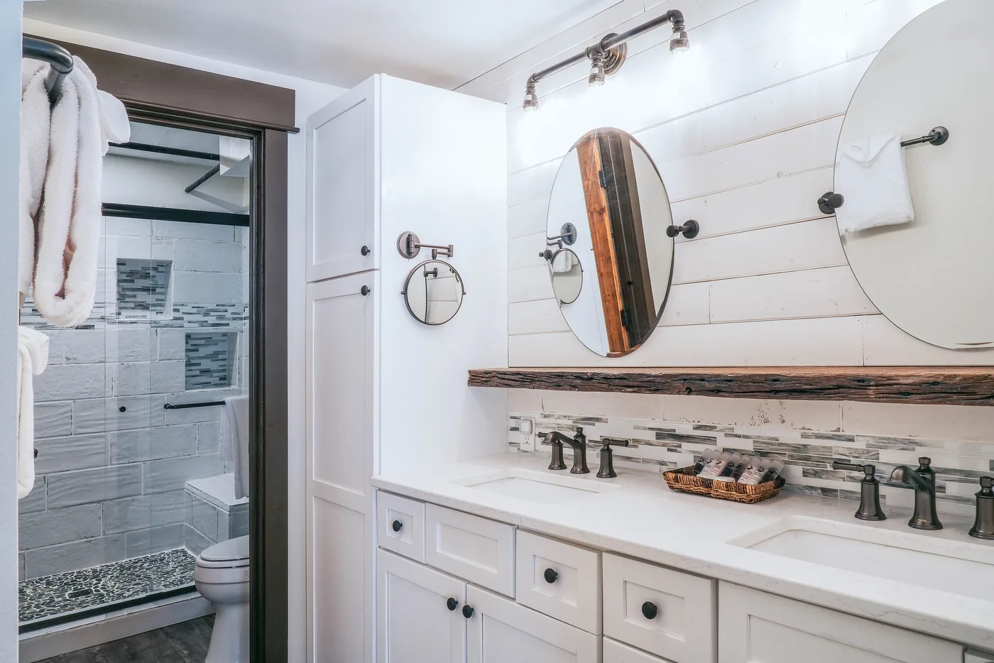 A bright bathroom with a long vanity, mirrors, and a tiled shower.