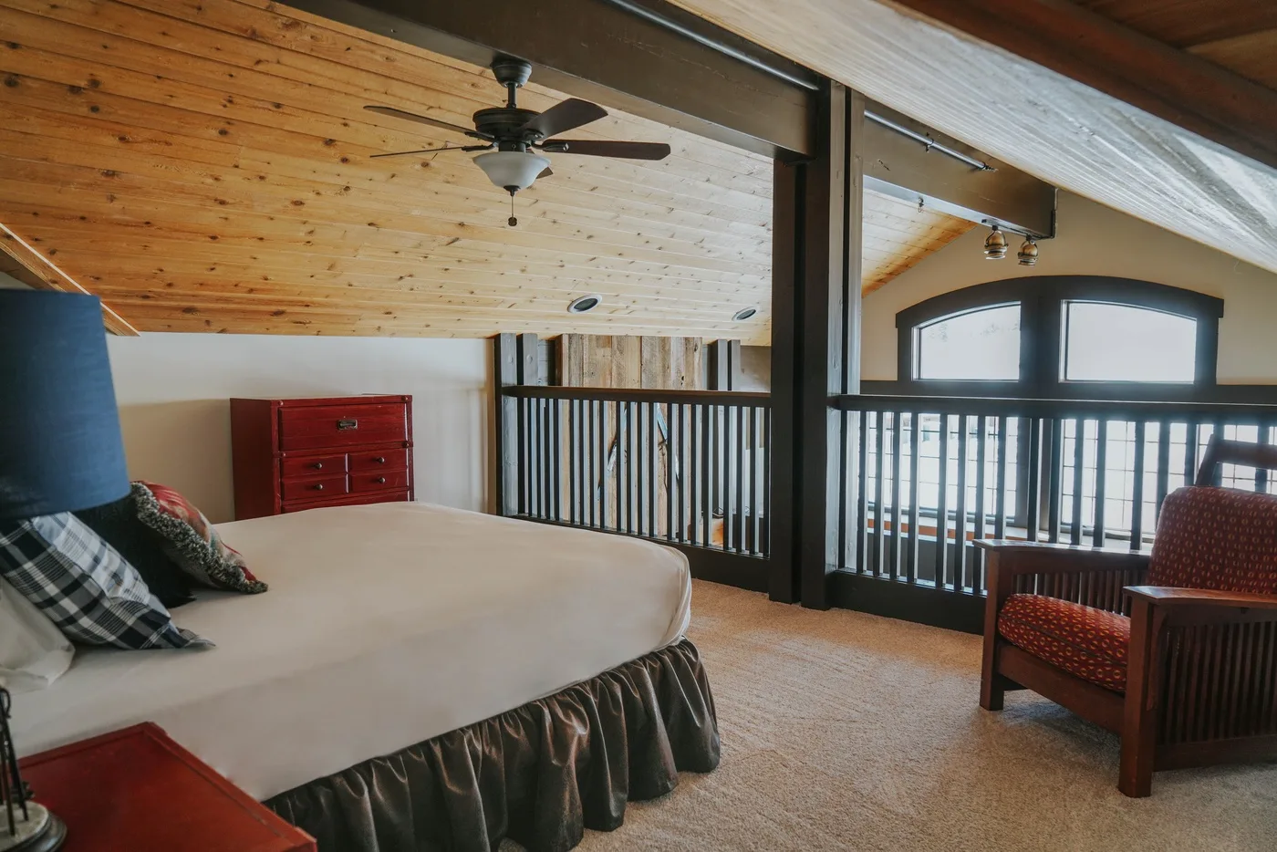 A bedroom with a bed and a railing overlooking the lower level.