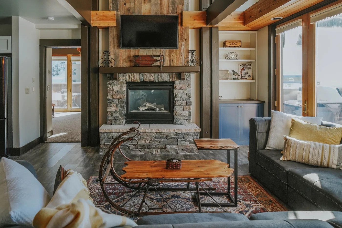 A living room with a stone fireplace, television, and seating around a coffee table.