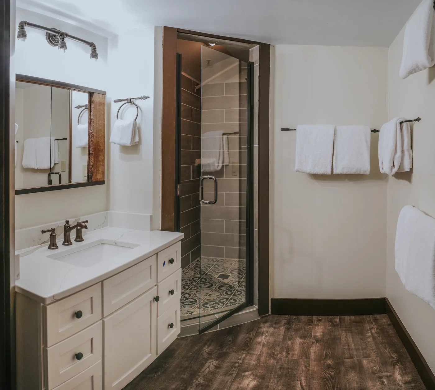A bathroom with a vanity beside a glass-enclosed shower.