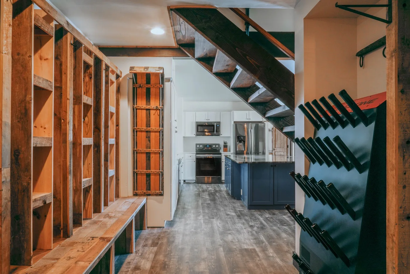 A kitchen with dark cabinetry and a staircase overhead.