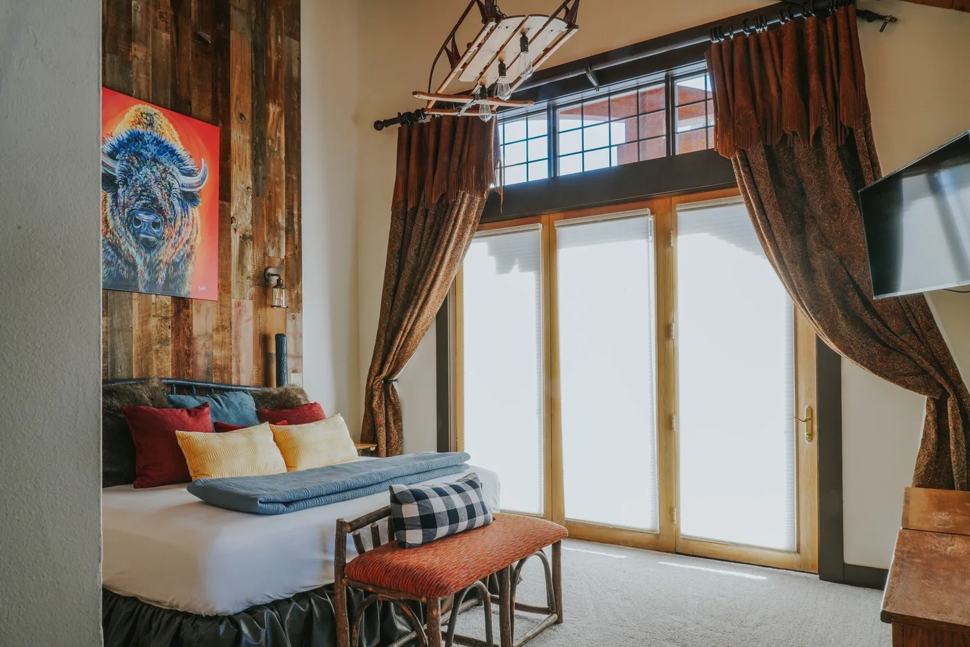 A bedroom with a bed beside tall glass doors and dark curtains.