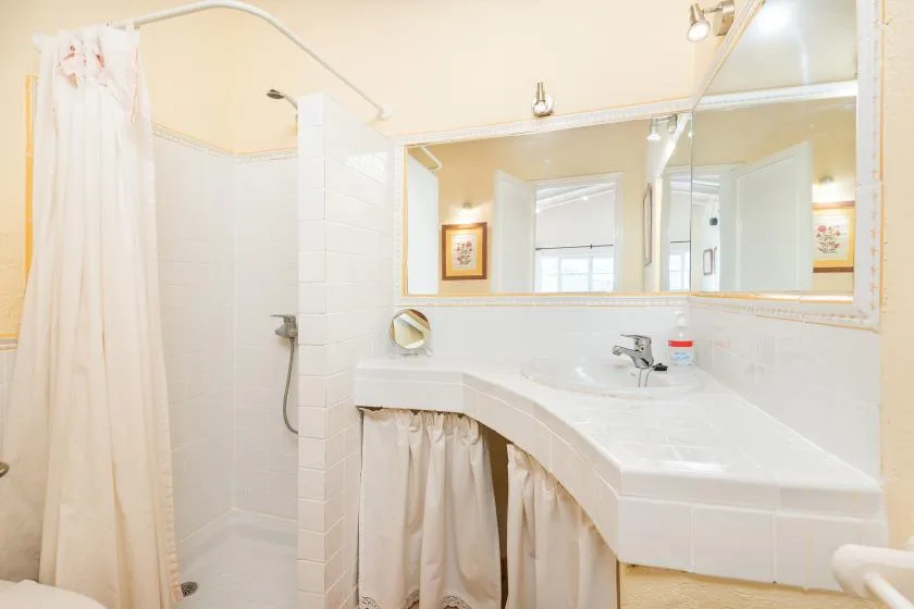 A bright bathroom with a curved vanity and a shower curtain.