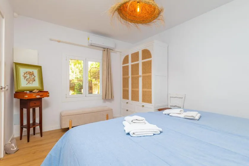 A bedroom with blue bedding, a window, and a wardrobe.