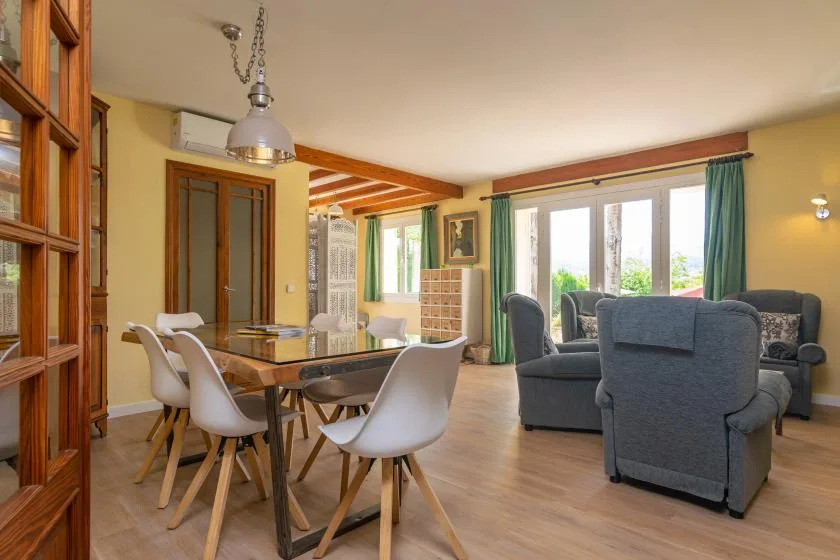 A combined living and dining area with a wooden table and seating by the windows.