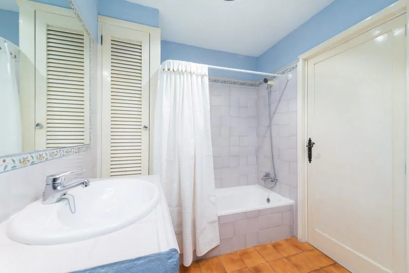 A bathroom with a sink and a bathtub behind a shower curtain.