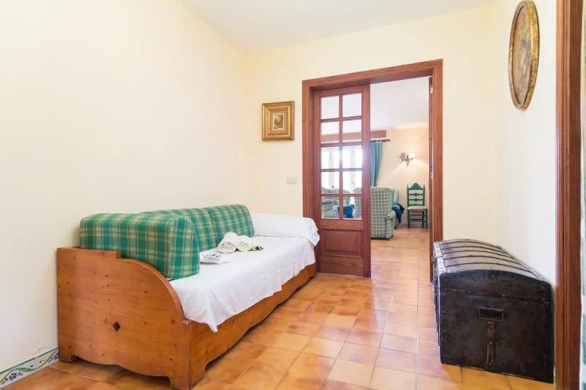 A bedroom with a single bed beside a wooden doorway opening into another room.