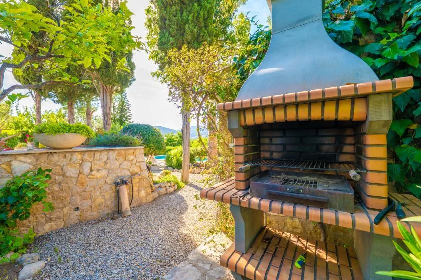 An outdoor patio with a brick barbecue beside a stone garden wall.