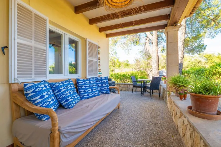 A covered patio has cushioned seating and a small outdoor dining set.