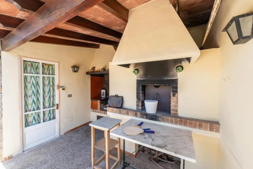 A rustic kitchen with a large fireplace and a small table.