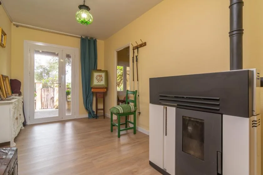 A living room with a green chair and a freestanding fireplace.