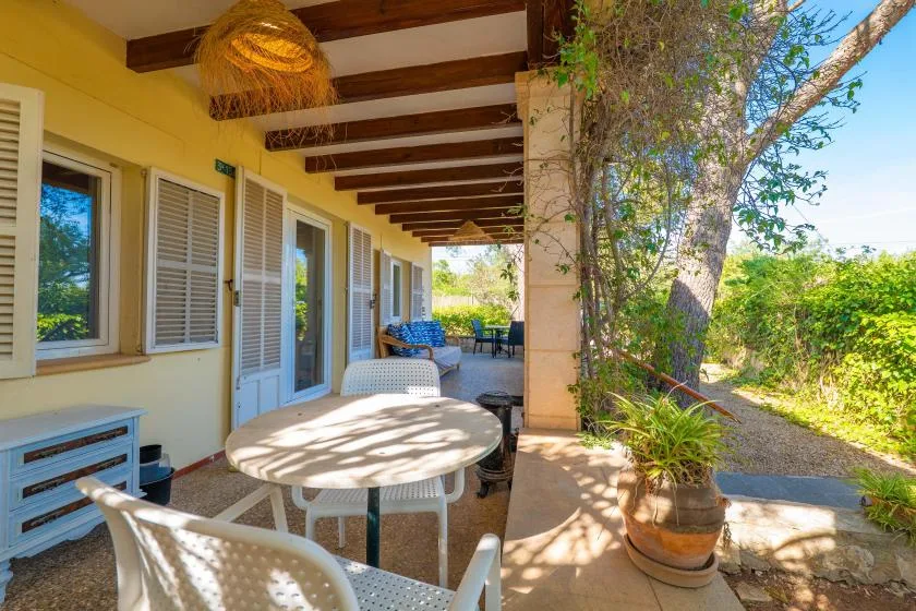 A covered outdoor patio with a round table and seating beside the garden.