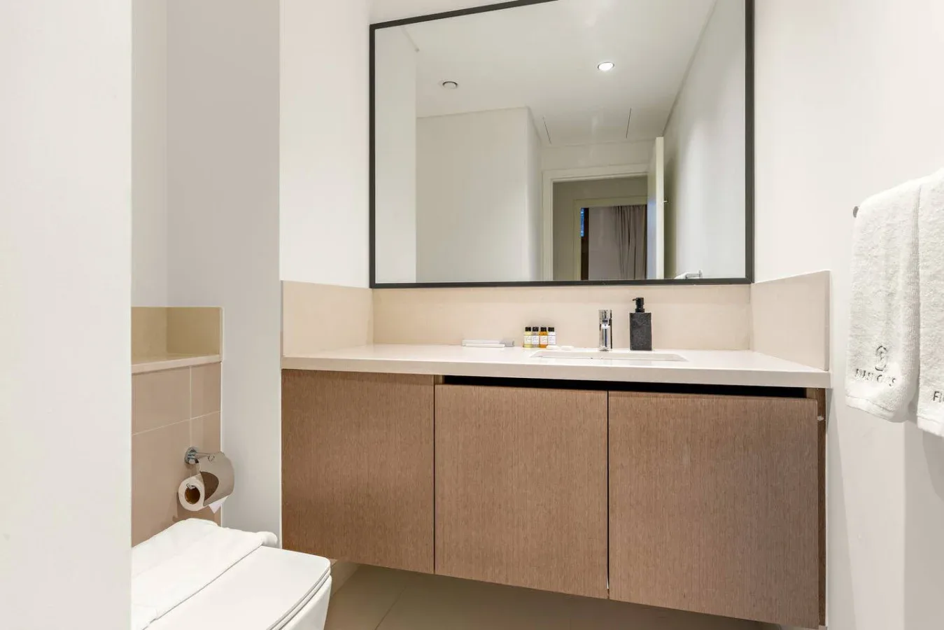 Un lavabo de baño con un espejo amplio y toallas colgadas cerca.