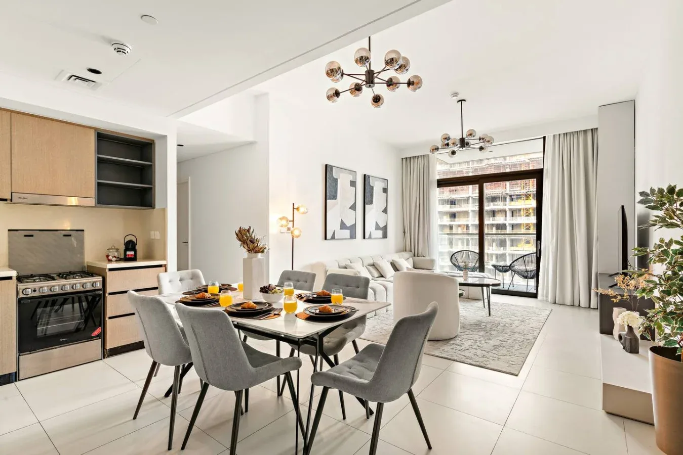 Una luminosa sala-comedor de concepto abierto con cocina y ventanales.