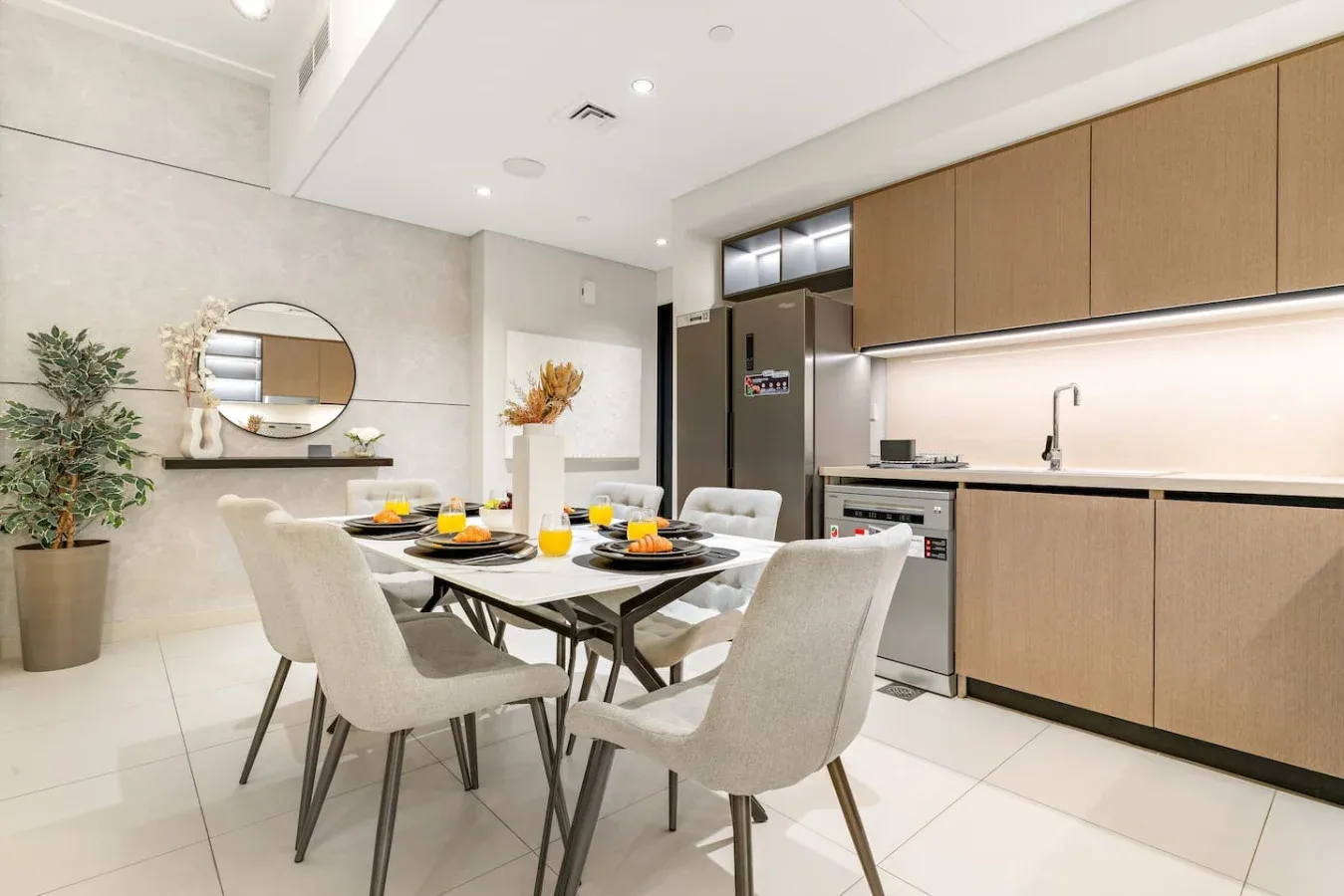 Una cocina moderna y zona de comedor con la mesa puesta y asientos claros.