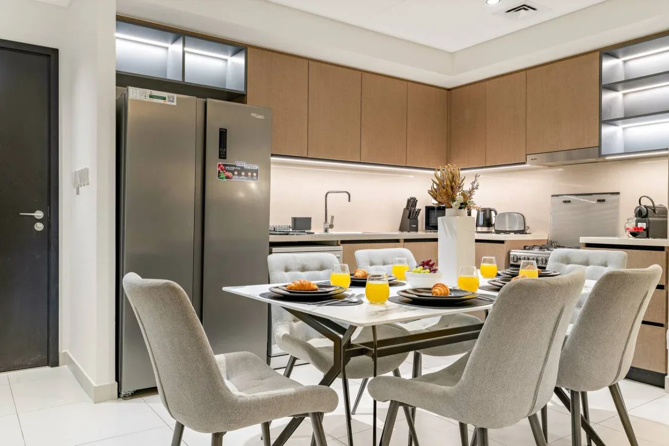 Una cocina moderna y zona de comedor con una mesa puesta con platos y vasos.